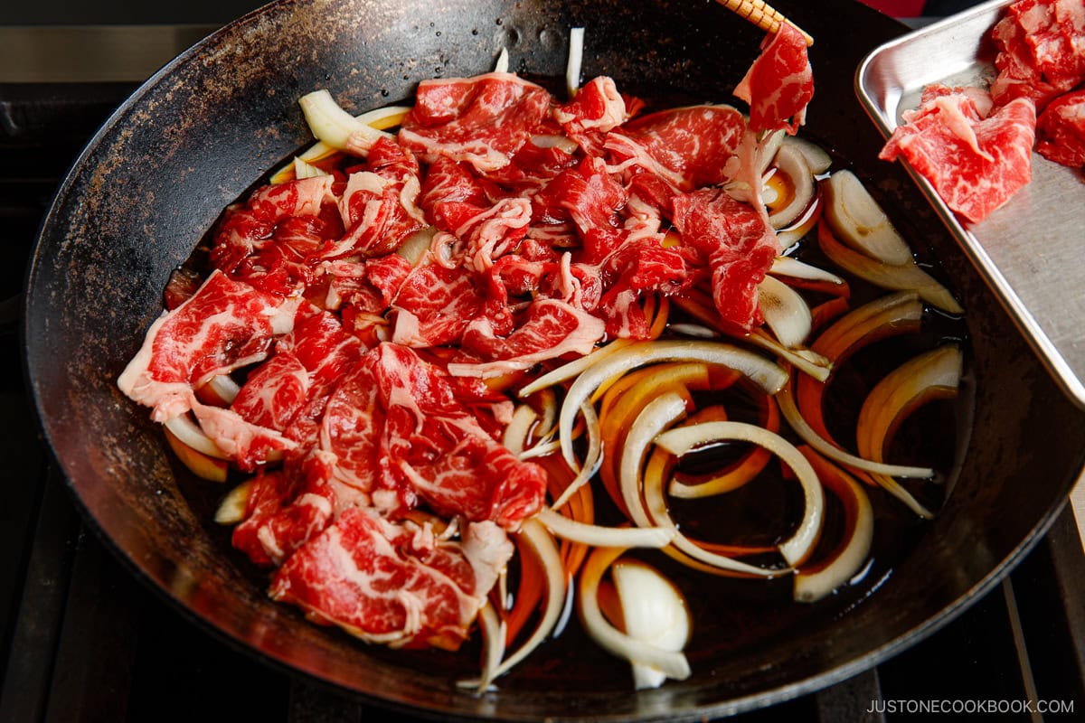 Add the thinly sliced beef over the onion slices.