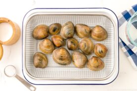Clams being cleaned over a wire rack.