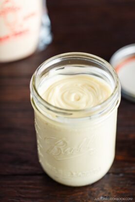 A mason jar of homemade Japanese mayonnaise next to a bottle of Kewpie mayonnaise.