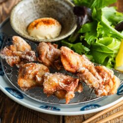 Beautiful Japanese plates containing karaage, Japanese fried chicken, garnished with lemon wedges and kewpie mayo dollop sprinkled with shichimi togarashi.