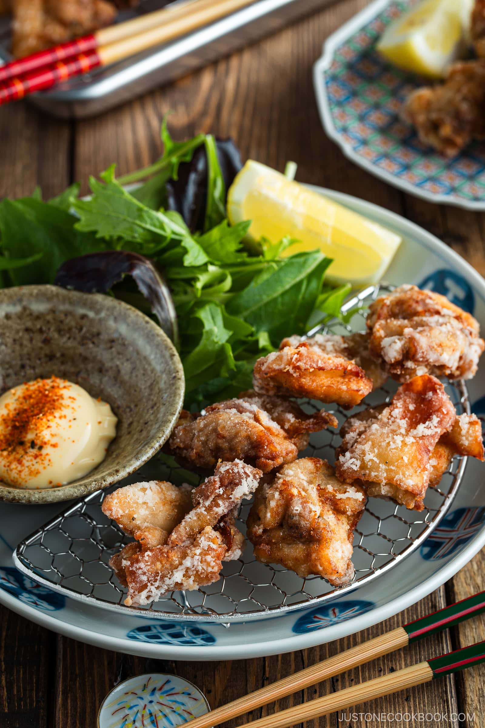 Beautiful Japanese plates containing karaage, Japanese fried chicken, garnished with lemon wedges and kewpie mayo dollop sprinkled with shichimi togarashi.