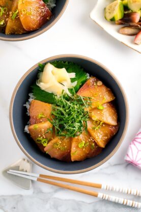 A ceramic bowl containing miso marinated hamachi served on bed of steamed rice along with shiso, scallion, and sushi ginger.