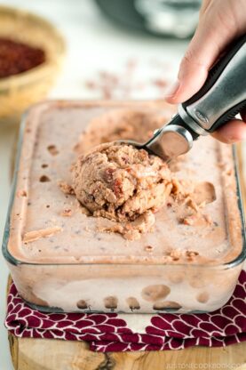 Ice cream server scooping off red bean ice cream from the glass container.